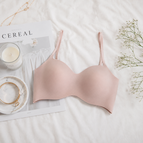 Beige Wacoal seamless bra laid flat on white bedlinen